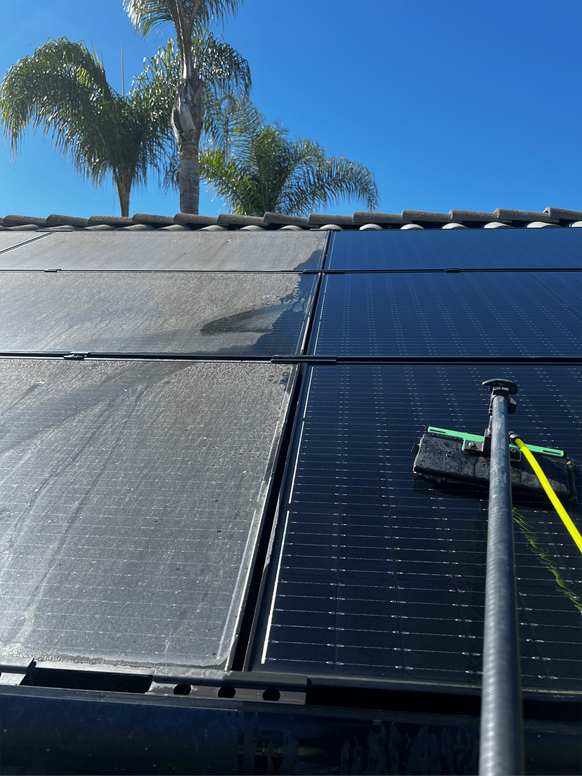 Solar panel being cleaned, showing a clear before and after effect with one side dirty and the other clean.