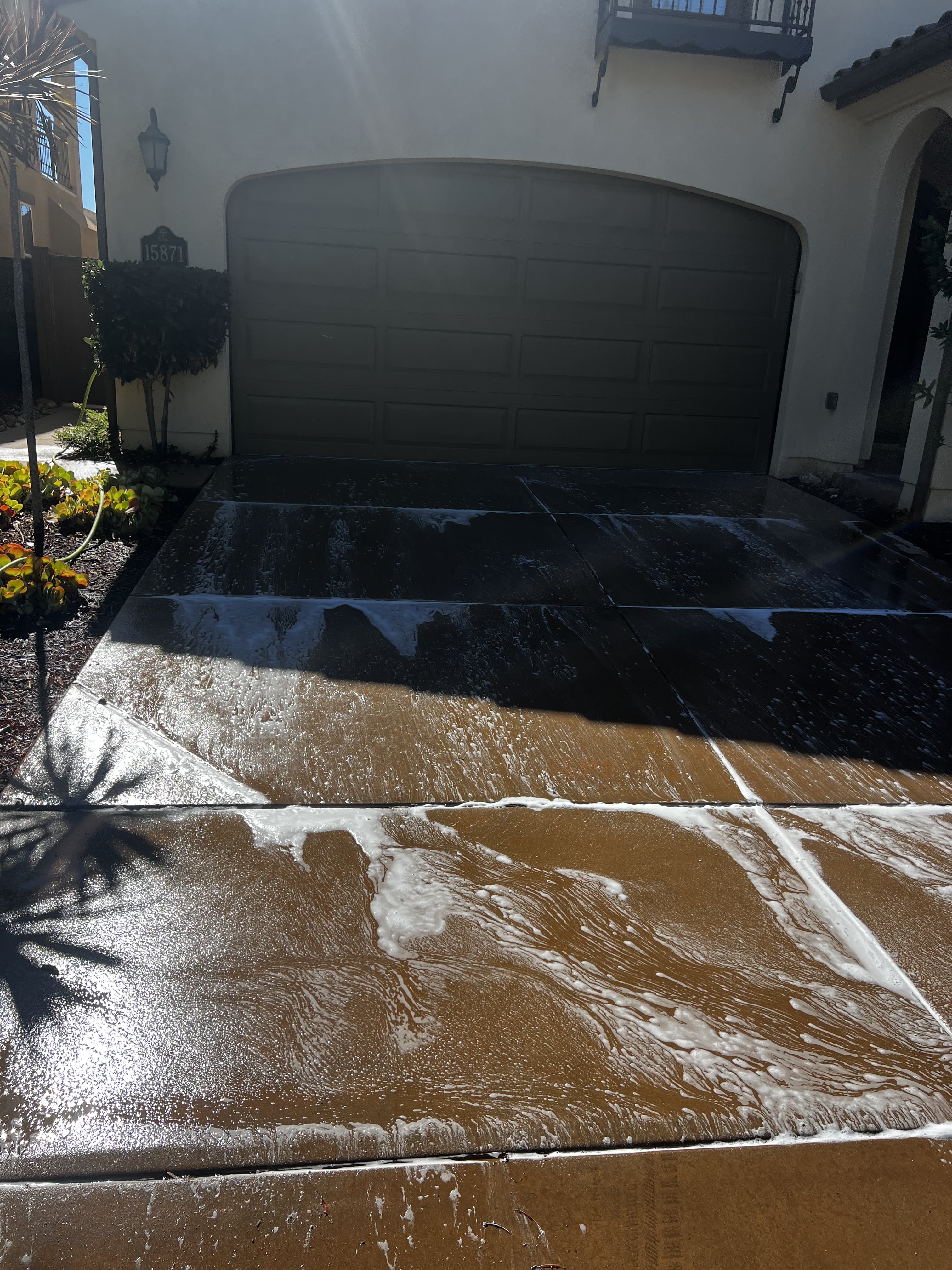Driveway being pressure washed with foam and water
